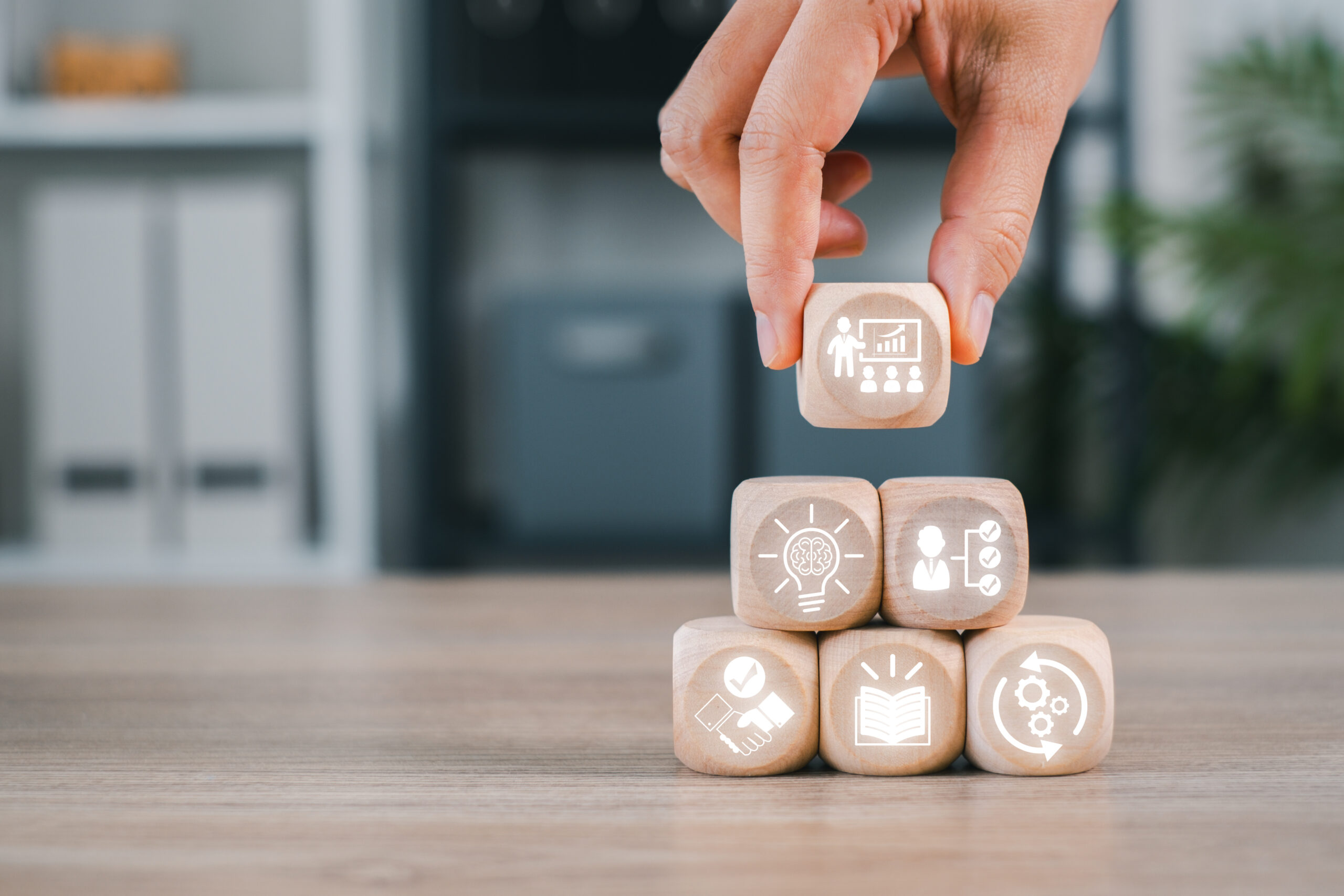 Wooden blocks with icons symbolize capacity building, showcasing growth, development, and skill enhancement in a professional setting.